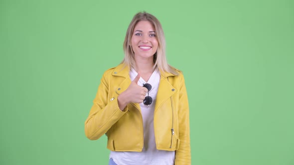 Happy Young Rebellious Blonde Woman Giving Thumbs Up alt