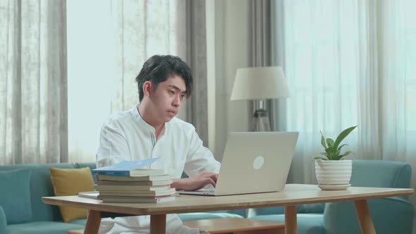 Asian Man Student Using Computer To Study Online At Home alt