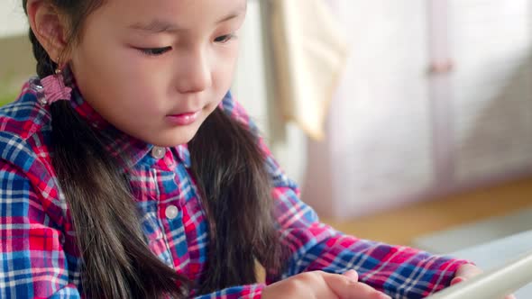 Little Asian Girl Browsing the Net on Tablet