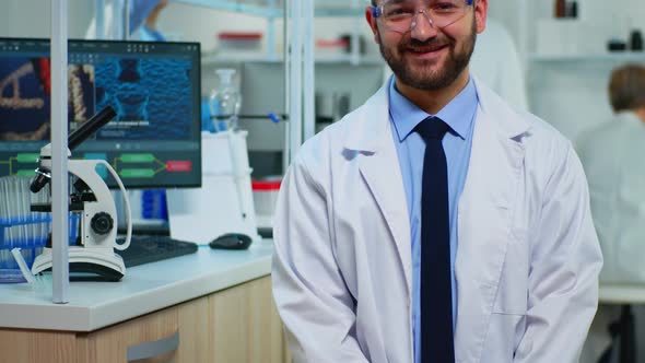 Portrait of Scientist Man Smiling at Camera Sitting in Modern Laboratory alt