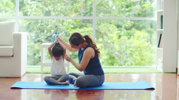 Young mother is teaching basic yoga postures for daughter
