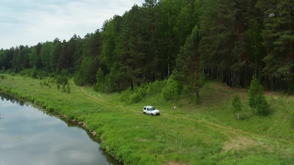 Aerial View of a Car Driving Along the River Bank alt