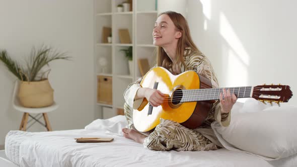 Happy Beautiful Woman Playing Guitar in Morning alt