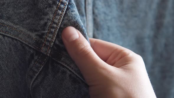 Male Hand Touches Blue Denim Jeans Jacket Checking Quality in the Clothing Store