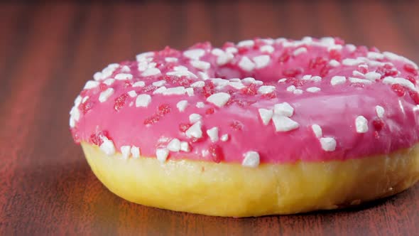 Fresh Doughnut with Pink Cream Rotates Under Electric Light alt