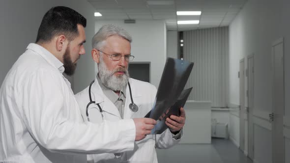 Two Male Doctors Discussing Xray Scans of a Patient at the Clinic
