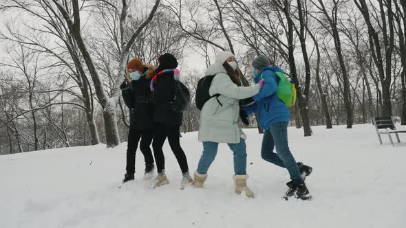 Schoolchildren Wearing Masks Throw Snowballs in the Park in Winter alt