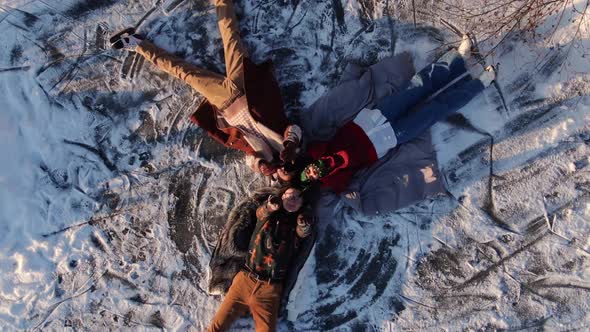 Young Friends in Vintage Clothes Make a Snow Angel alt