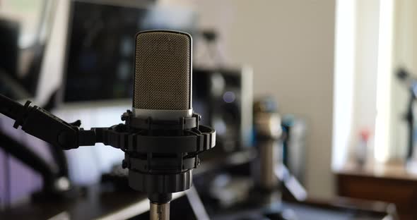 A professional condenser microphone in a music studio for recording a singer or vocalist SLIDE LEFT. alt