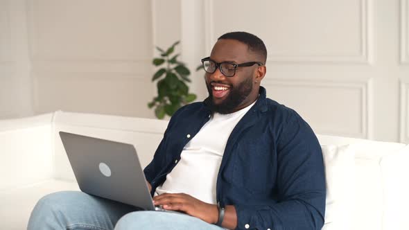Hilarious AfricanAmerican Guy Using Laptop for Remote Video Connection alt