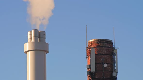The chimney from the factory emits dirty smoke, there is an old red brick