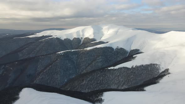 Amazing Aerial Flight Over Misty Mountain Range Meadows and Snow Covered Peaks in Winter Time alt
