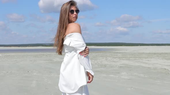 Charming Woman Standing on Beach on Windy Day