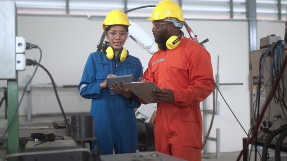 specialist engineer co-worker male and female standing discuss consult robot arm welding