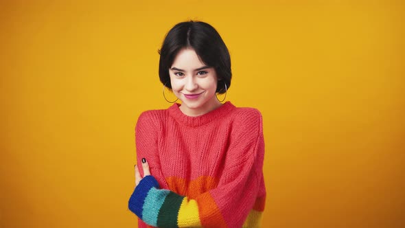 Cute Woman Wearing Red Sweater with Rainbow Sleeves Showing Bellissimo Gesture and Smiling to Camera alt