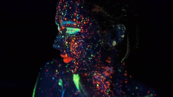Neon Paint on the Girl's Face. Portrait of a Young Woman Painted with Luminous Paints alt
