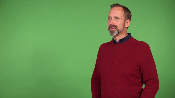 A Middleaged Handsome Caucasian Man Waves at the Camera with a Smile  Green Screen Background