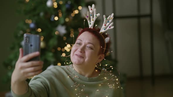 Middle-aged woman wishes her relatives Christmas via video call in smartphone