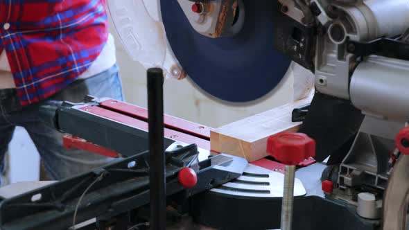 Close-up of Carpenter cutting wood with cutting machine in workshop