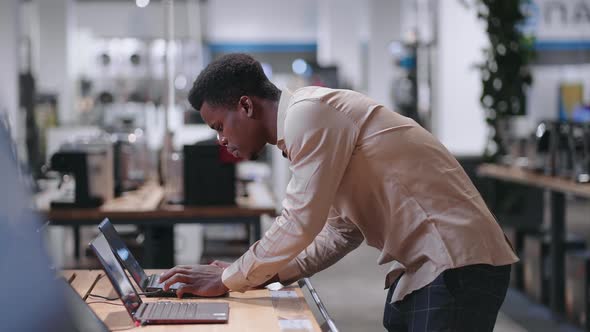 Afroamerican Man is Choosing Laptop in Electronics Store Viewing Exhibition Samples in Trading Hall alt