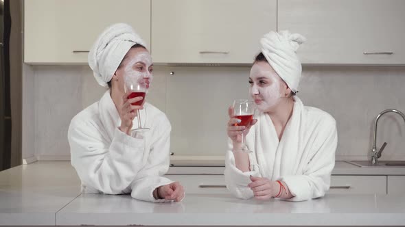 Two Friends in Robes and Towels on Their Heads Have Fun Drinking Wine