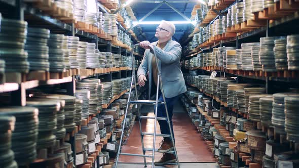 Archivist is Using a Ladder to Get a Vintage Movie Tape alt