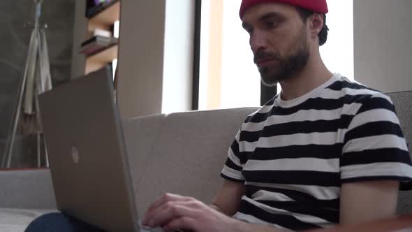 Guy - freelancer sitting on the couch, working on a laptop alt