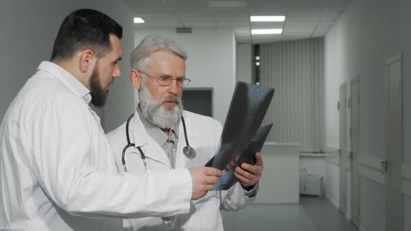 Two Male Doctors Discussing X-ray Scans of a Patient at the Clinic