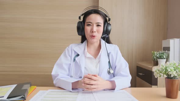 Young attractive Asian female doctor diagnosis talking and looking to camera alt