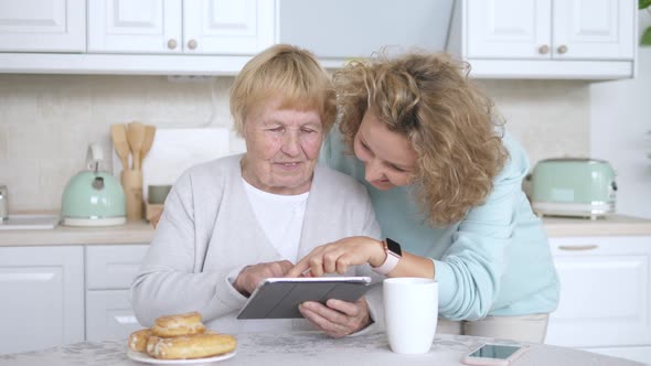 Granddaughter Teaching Grandmother How To Use A Tablet