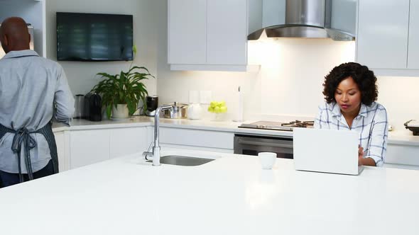 Couple using laptop in kitchen 4k alt