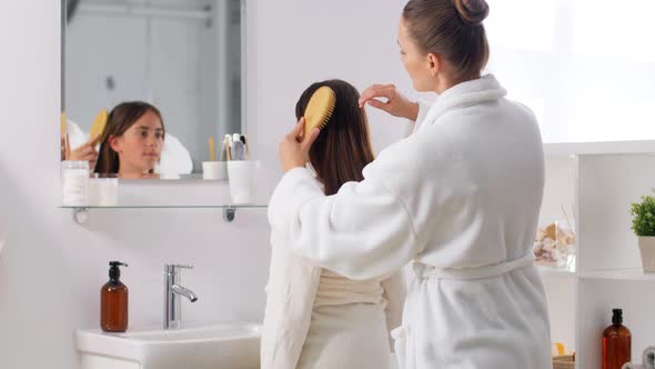 Mother and Daughter Brushing Hair in Bathroom