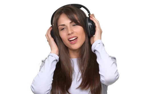 Happy Smiling Caucasian Girl Listening Music with Pleasure Through Black Headphones Over White alt