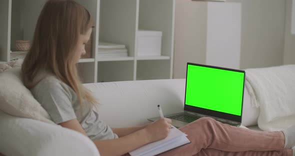 School Girl Is Viewing Online Lesson on Laptop with Green Screen for Chroma Key Technology,writing alt