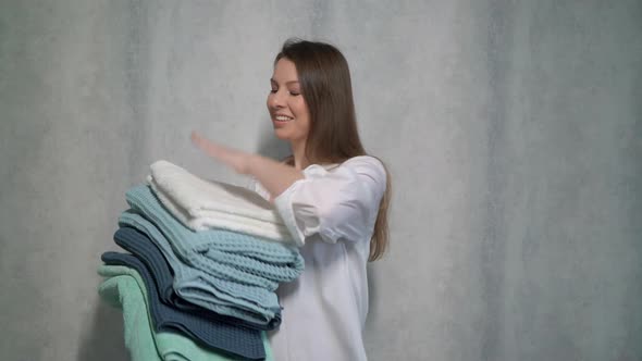 A Young Housewife Woman Holds a Stack of Fresh Washed Clean Linen in Her Hands alt