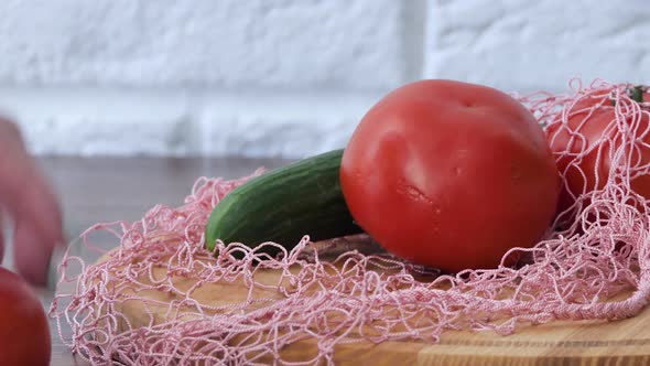 A Woman Takes Out Cucumber Tomatoes From a Reusable Grocery Bag Vegetables on a Table in the Kitchen
