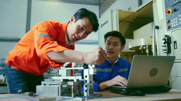 two asian coworker brainstorm  explaining and solves the process of the cnc operate machine