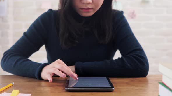 Woman college student concentrating on reading e-book from tablet computer at the table