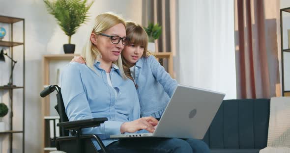 Girl Standing Near Her Pretty Positive Loving Disabled Mother in Wheelchair After Accident alt