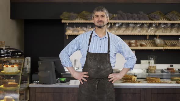 Friendly Male Baker Wipes His Hands on an Apron From Flour and Puts Hands on Hips alt