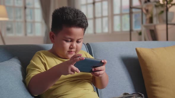 Boy Playing Game On Smartphone Sitting On Sofa, Talking While Playing A Game alt