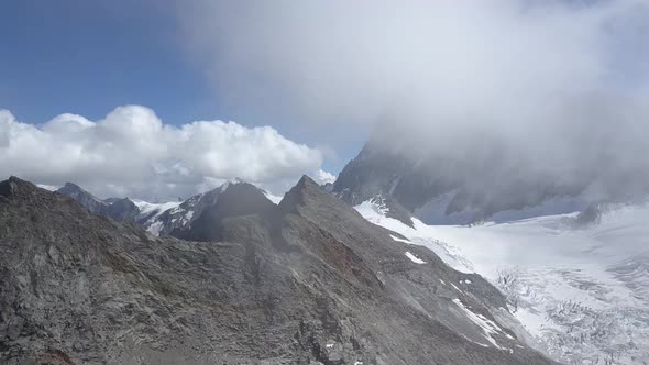 Aerial shot in the swiss alps discovering a wild montain range in the clouds alt