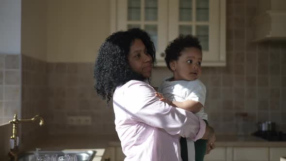 Side View Happy African American Young Mother Kissing Son As Father Bringing Soccer Ball alt