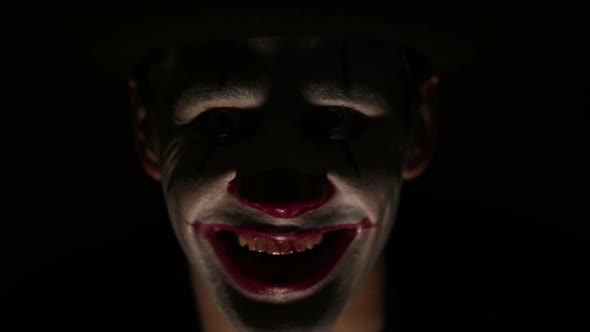 Scary Man in a Clown Makeup Looks at the Camera and Laughs