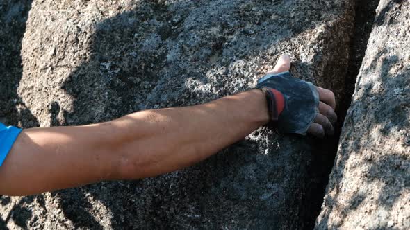 Closeup of a Gloved Climber's Hand Holding Onto a Rock Crack
