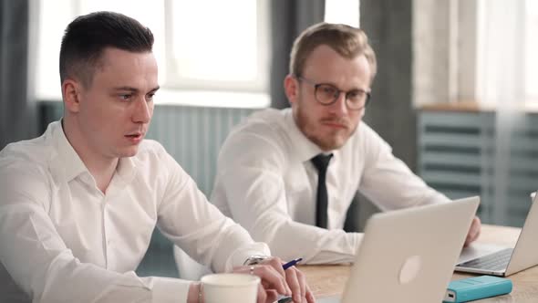 Businessmen Work Together at Two Laptops, Talk Discuss Collaborate Together. Men Sit at Desk