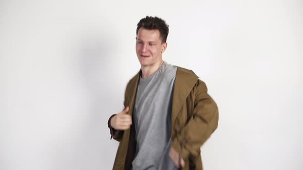 White Guy in a Brown Coat and a Funny Dance on a White Background. In a Good Mood. Positive Video. alt
