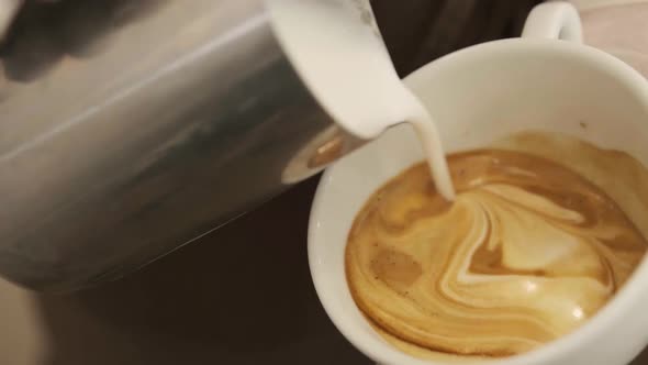 Close Up Barista Hands Pouring Warm Milk in Coffee Cup for Making Latte Art alt