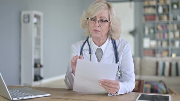 Professional Old Female Doctor Reading Documents alt