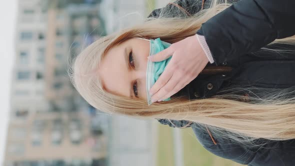 Female Putting a Medical Mask on Her Face on the Street alt